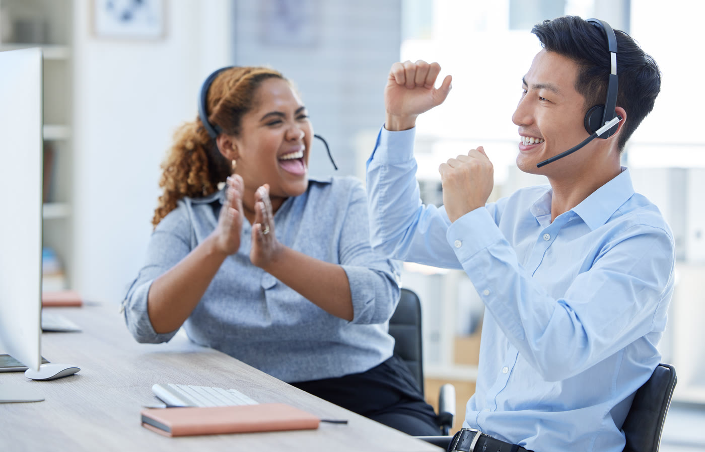 Two OnePageClick sales representatives celebrating a closed deal at their desk